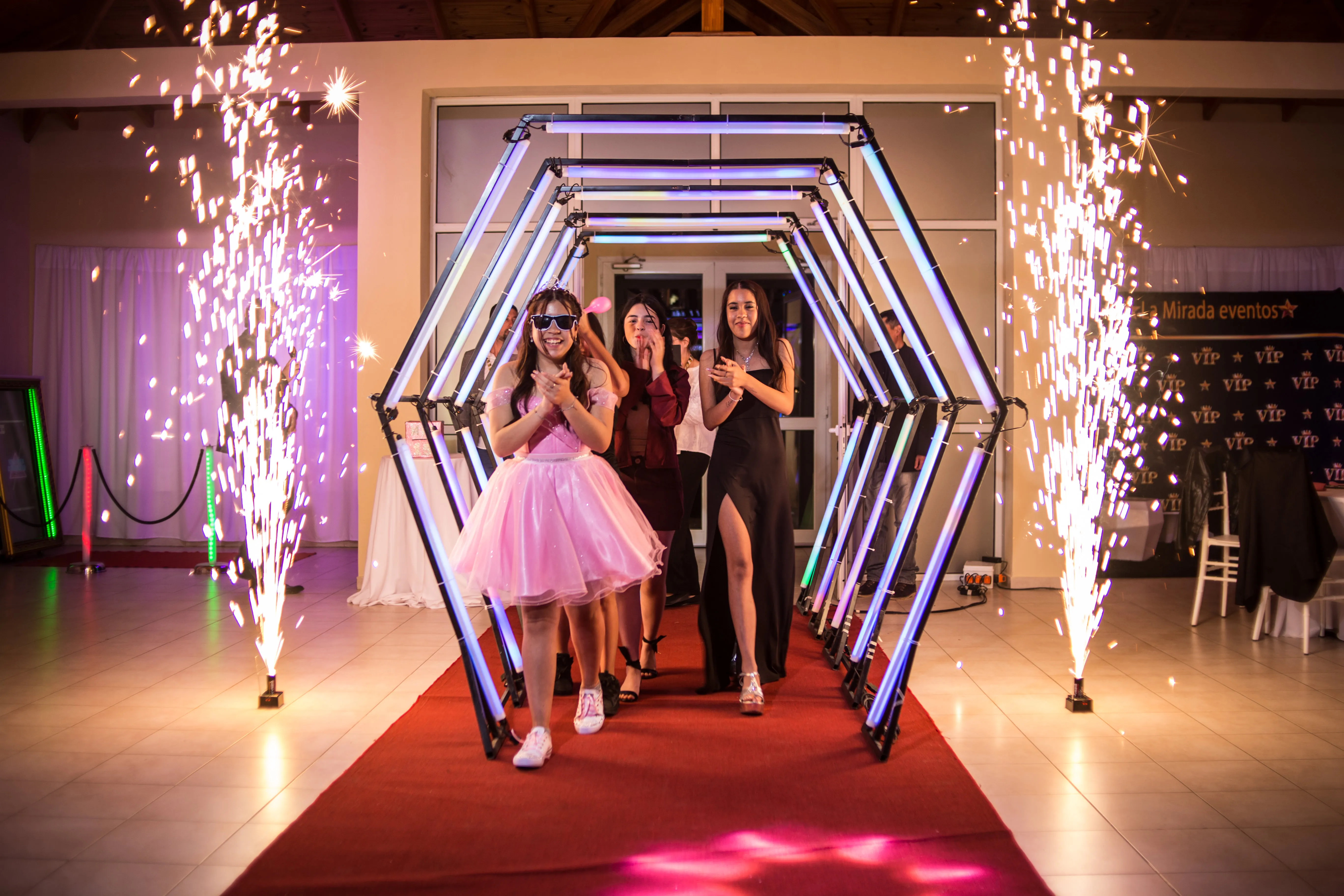 Quinceañera entrando al salón por el túnel iluminado entre bengalas frías