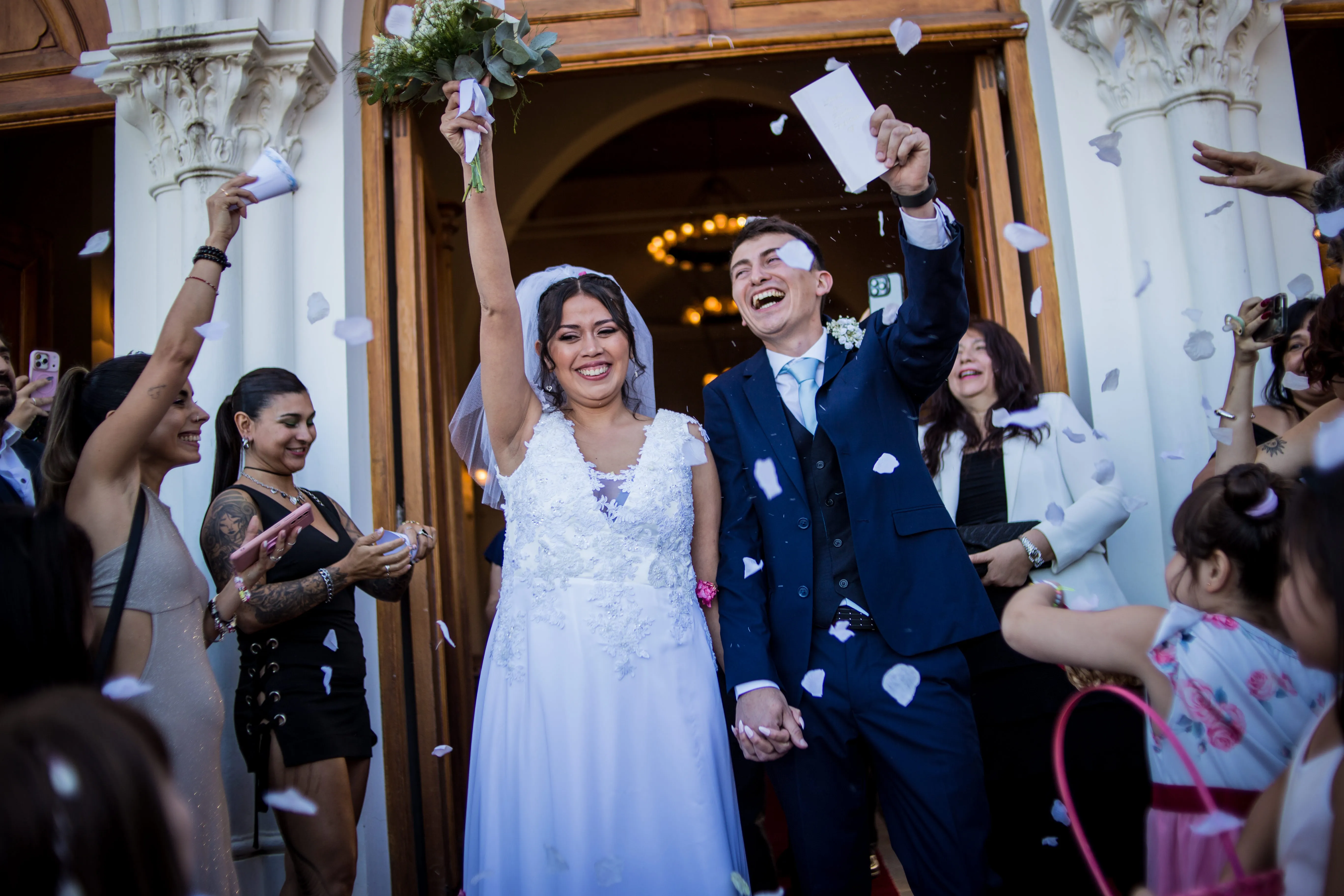 Recién casados saliendo de la iglesia entre pétalos y aplausos de los invitados